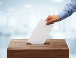48354981 - ballot box with person casting vote on blank voting slip